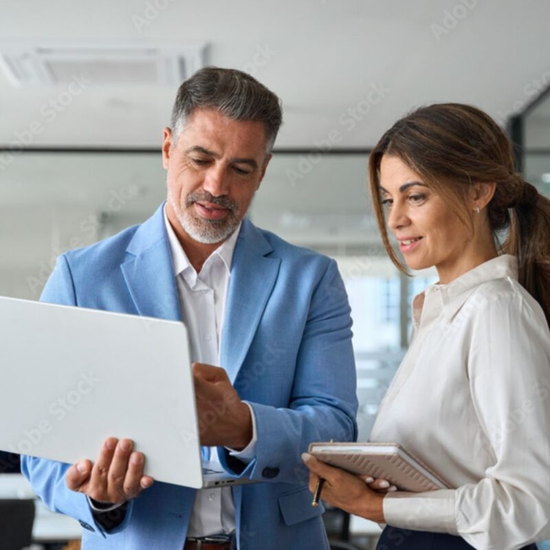 Two people discuss information while looking at a laptop