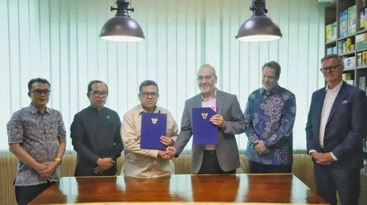 Men standing around a conference table, shaking hands and holding a document.