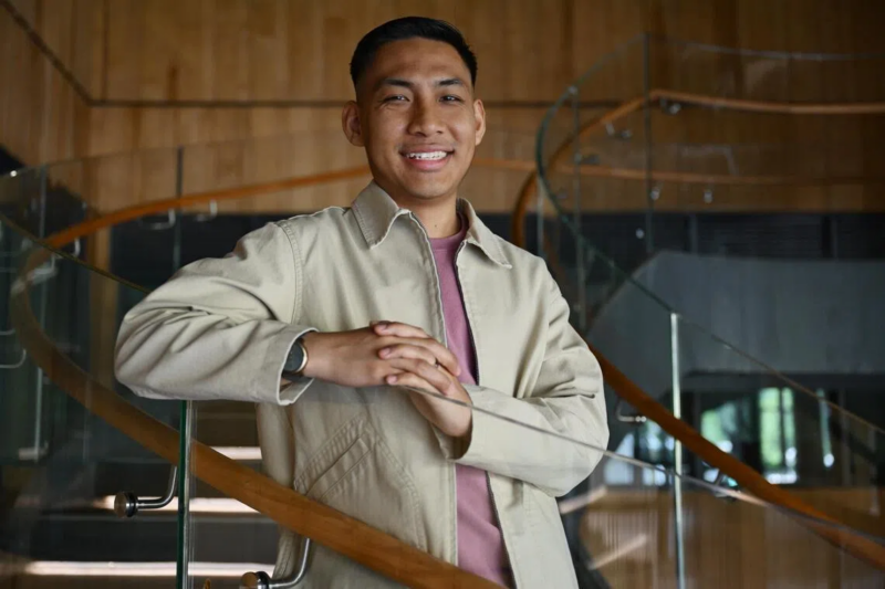 Man posed on staricase for picture with hands leaning on railing.