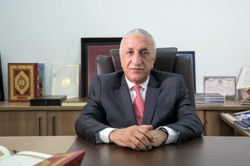man sitting at a desk in a suit and tie.